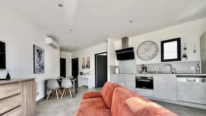 Una cocina moderna con armarios grises, un reloj grande y un televisor de pantalla plana.