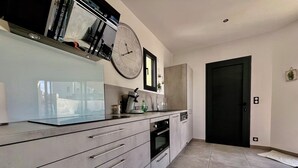 Una cocina moderna con un reloj grande, electrodomésticos de acero inoxidable y un diseño minimalista.