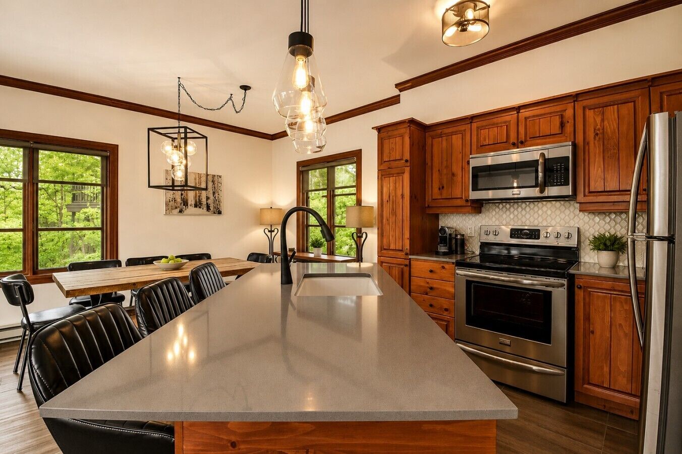 A kitchen with wooden cabinets, stainless steel appliances, a large island, and pendant lighting.