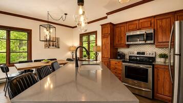 A kitchen with wooden cabinets, stainless steel appliances, a large island, and pendant lighting.