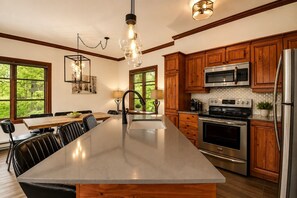 A kitchen with wooden cabinets, stainless steel appliances, a large island, and pendant lighting.