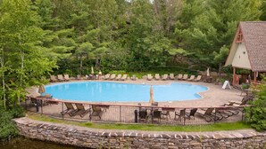 Une piscine entourée d’un mur de pierre, avec des chaises longues et des parasols tout autour.