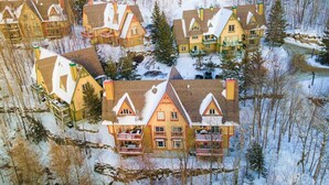 Un ensemble de maisons traditionnelles en bois, dotées de nombreux balcons, entouré d’une forêt enneigée.