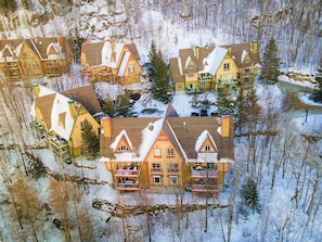 Een groepje traditionele houten huizen met meerdere balkons, omgeven door een besneeuwd bos.