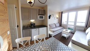 Et kompakt hotelværelse med tekøkken, sofa, spisebord og seng.