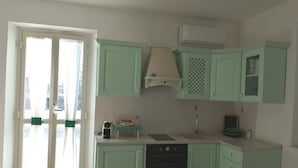 Eine Küche mit hellgrünen Schränken, einem eingebauten Backofen und einem Fenster mit Vorhängen.
