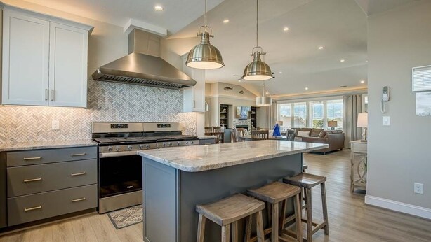 A modern kitchen with a large island, stainless steel appliances, and pendant lighting.