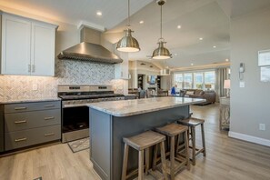 A modern kitchen with a large island, stainless steel appliances, and pendant lighting. - X-TA-SEA | 440 ft to the beach | Private Pool, Hot Tub, Dog-Friendly (Virginia Beach)