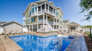 A two-story house with a swimming pool in front.