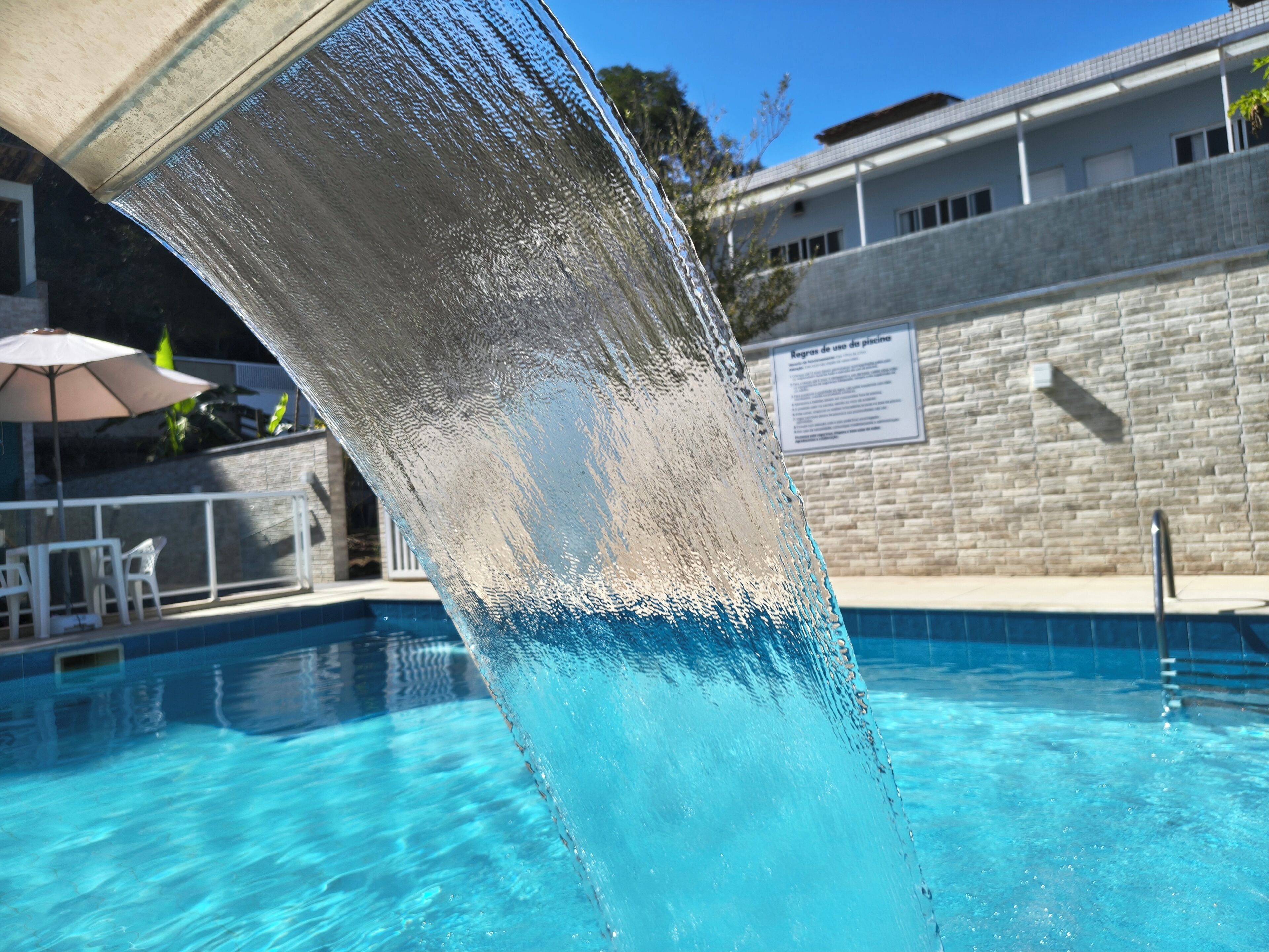 Une piscine à l’eau claire, avec une barrière en verre et un mur carrelé en arrière-plan.
