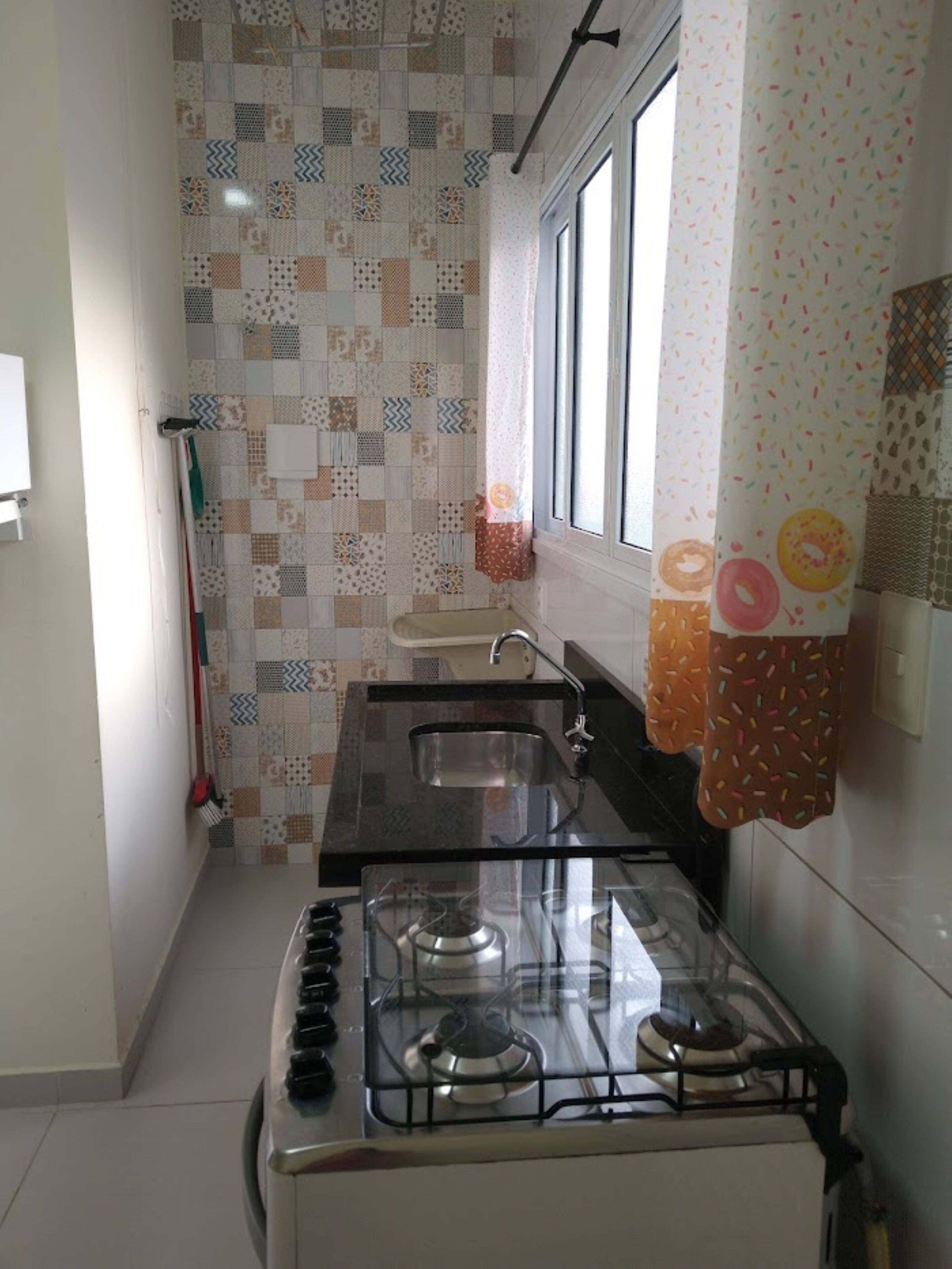 Una cocina con estufa a gas, un lavamanos y un ventanal.