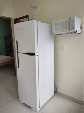 Eine kleine Küche mit einem weißen Kühlschrank, einer Mikrowelle und einem Holzrahmen an der Tür.
