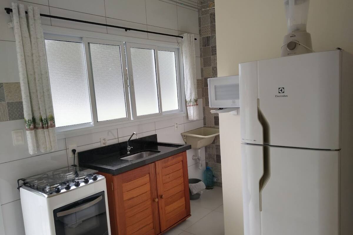 A kitchen with a stove, sink, cabinets, and a refrigerator.