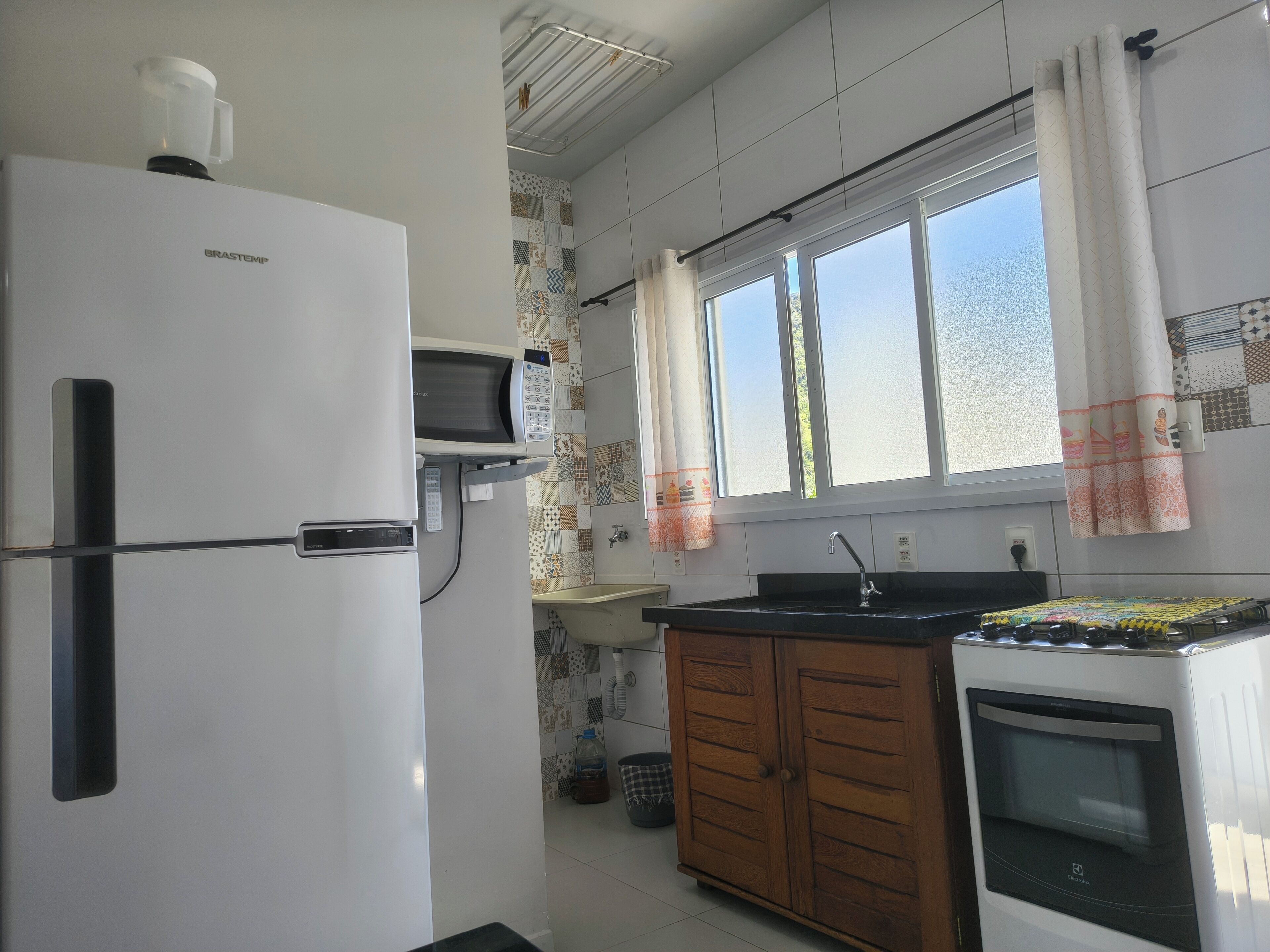 A compact kitchen with a refrigerator, microwave, sink, and oven.