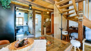 A rustic interior with a wooden staircase, a kitchen area, and a dining space with a basket of food. - Lovely home in Starcevljani (Starcevljani)