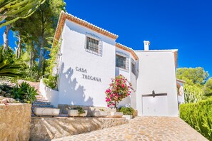A white building with the sign "CASA TOSCANA" on the facade, a tiled entrance, and a stone pathway leading up to it.