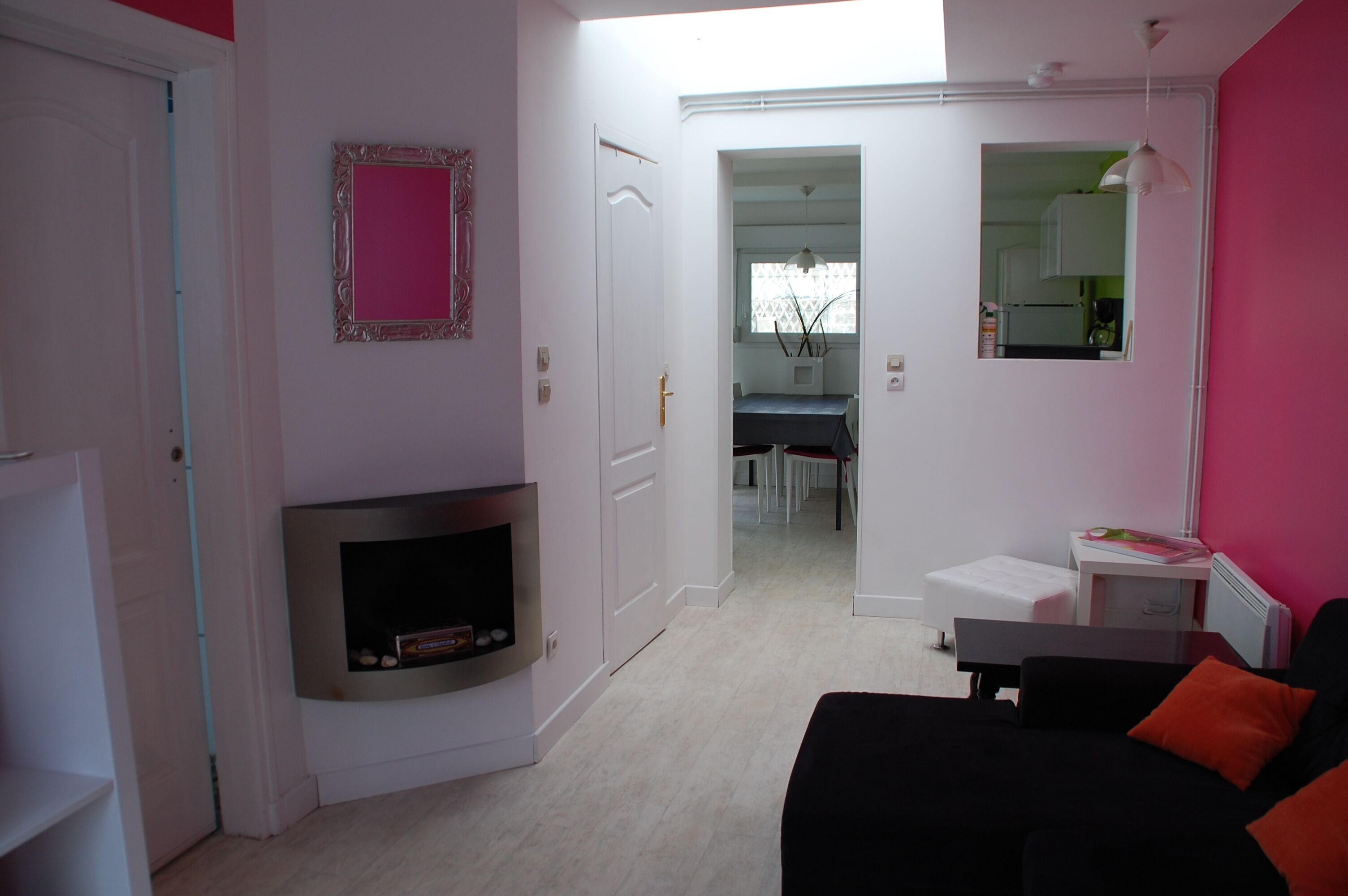 Un salon moderne avec une cheminée, un coin repas et une cuisine visible à travers une porte ouverte.