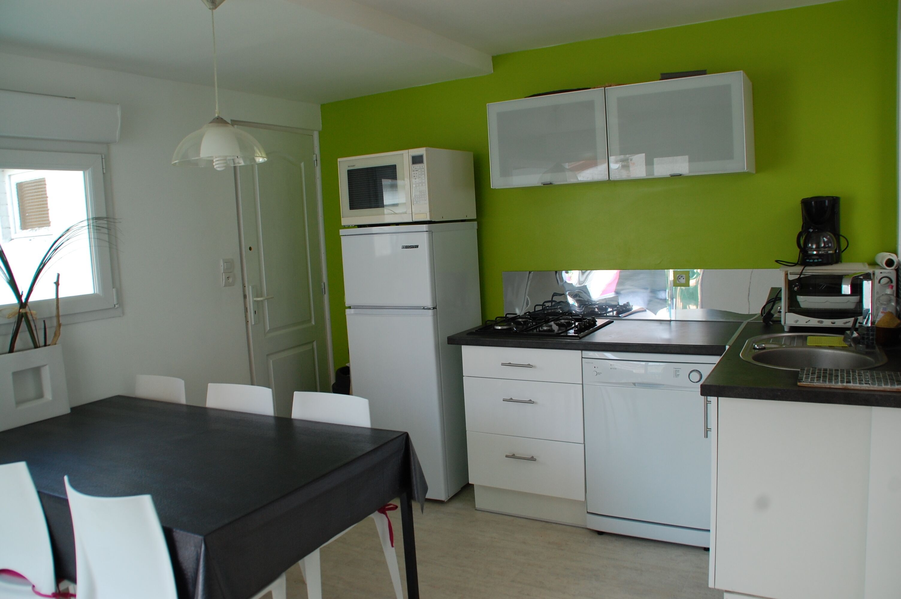 Cocina compacta con refrigerador, microondas, estufa y cafetera.