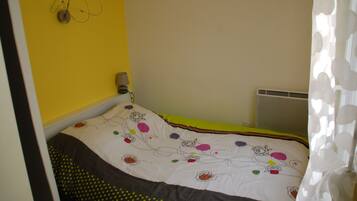 A bedroom with a bed, a wall-mounted lamp, and a radiator.