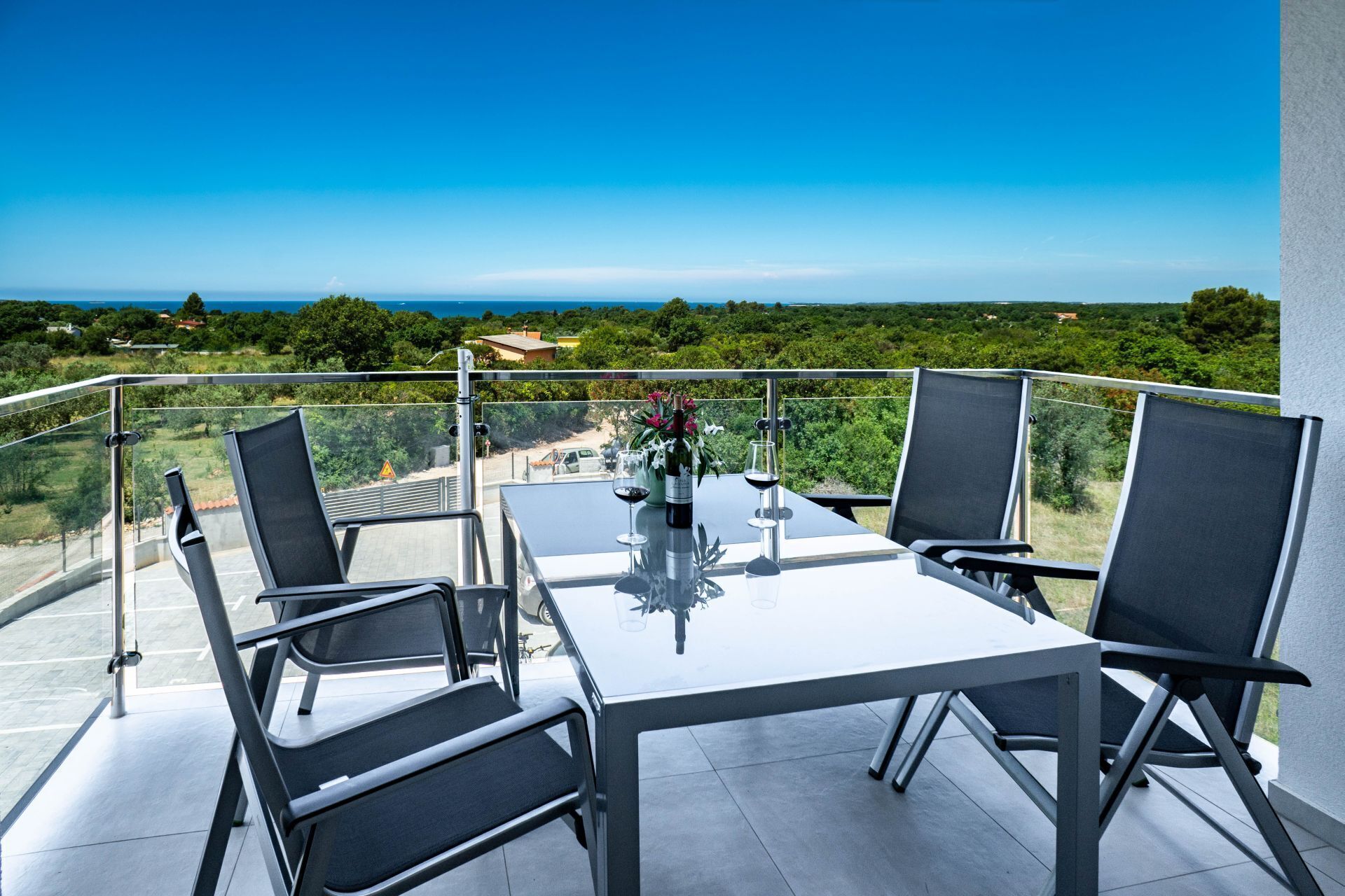 Un balcon avec une table et des chaises, donnant sur un paysage pittoresque.