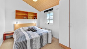 Une chambre à coucher avec un lit, une fenêtre, une armoire et une étagère remplie de livres.