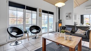 Un salon moderne doté d’une cheminée, de grandes fenêtres et d’un coin salon confortable.