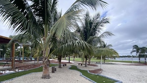 Een aangelegde tuin met palmbomen, een volleybalnet en een pad met stenen.