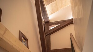 A wooden staircase with a handrail, wooden beams, and a framed picture on the wall. - Nouveau Duplex Centre Village vue sur L'eglise et Terrasse sud (La Clusaz)