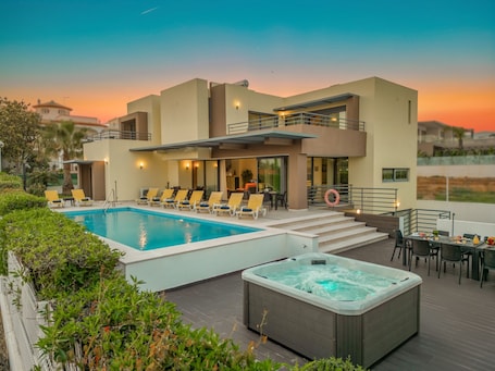 A modern hotel with a swimming pool, a hot tub, and a terrace with outdoor seating.