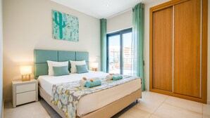 A hotel room with a bed, a nightstand, a window with curtains, and a wooden door. - Exclusive villa with jacuzzi and heatable pool (Armação de Pêra)