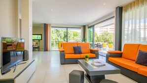 A modern living room with orange sofas, a flat-screen TV, and a balcony with yellow chairs. - Exclusive villa with jacuzzi and heatable pool (Armação de Pêra)