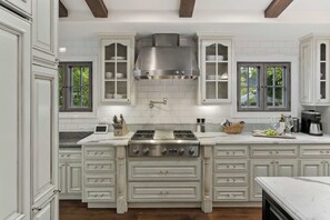 Keittiössä on valkoiset kaapit, ruostumattomasta teräksestä valmistettu liesi ja sisäänrakennettu liesituuletin.