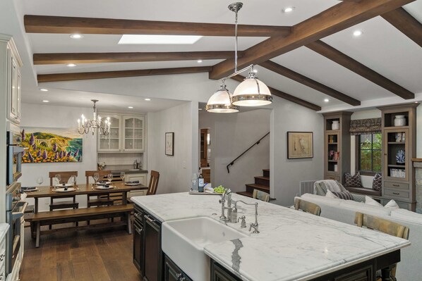 Una cocina amplia con una isla grande, vigas de madera e iluminación colgante.