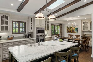 A spacious kitchen with a large island, built-in appliances, and a dining area with a chandelier.