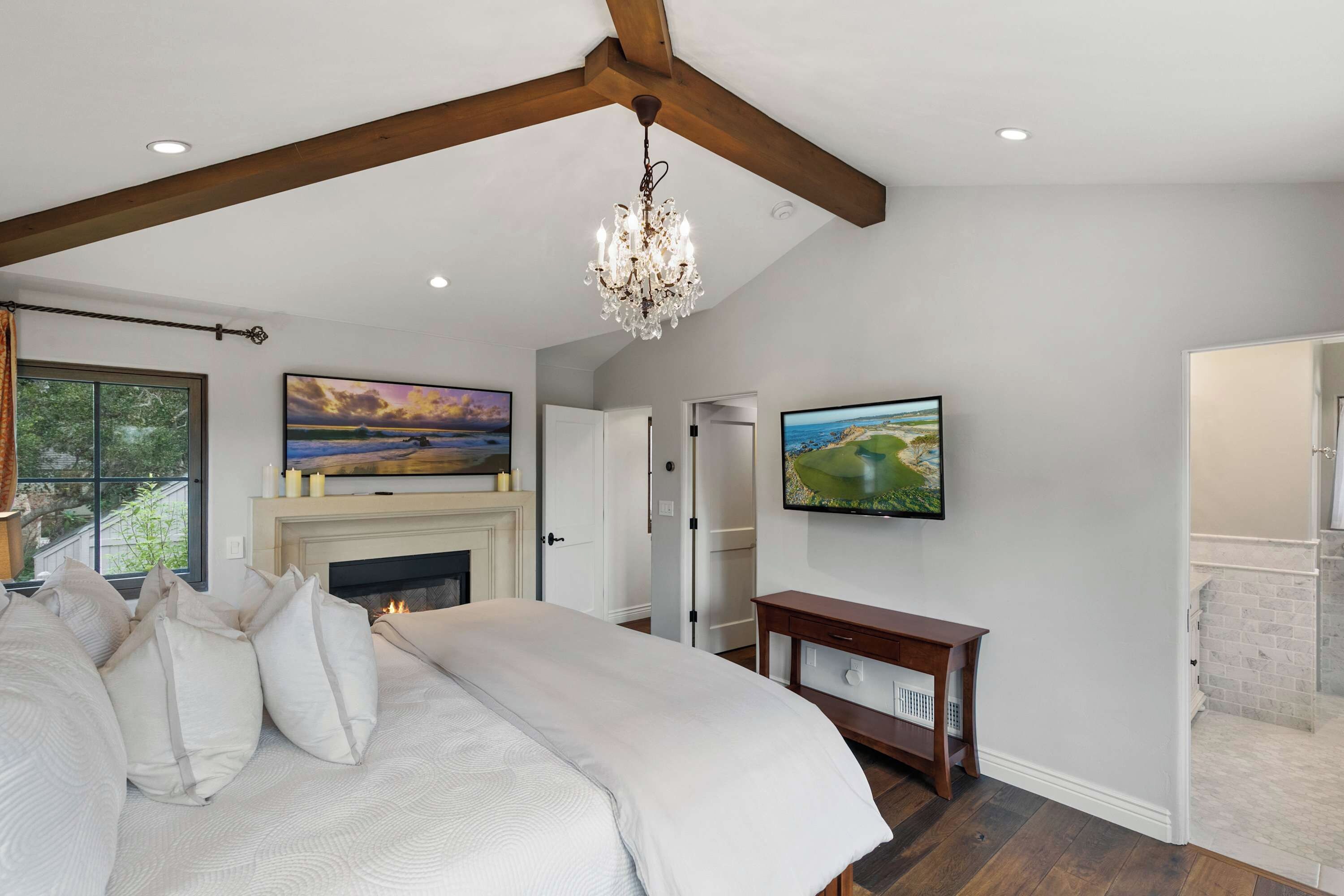 Een slaapkamer met een bed, een open haard, een kroonluchter en twee schilderijen aan de muur.