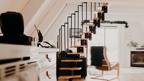 Ein modernes Loft mit einer Holztreppe, einem Kamin und einer gemütlichen Sitzecke.