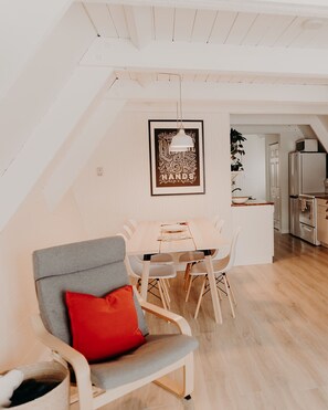 Une cuisine moderne avec des armoires blanches, un plan de travail en bois et un luminaire suspendu.