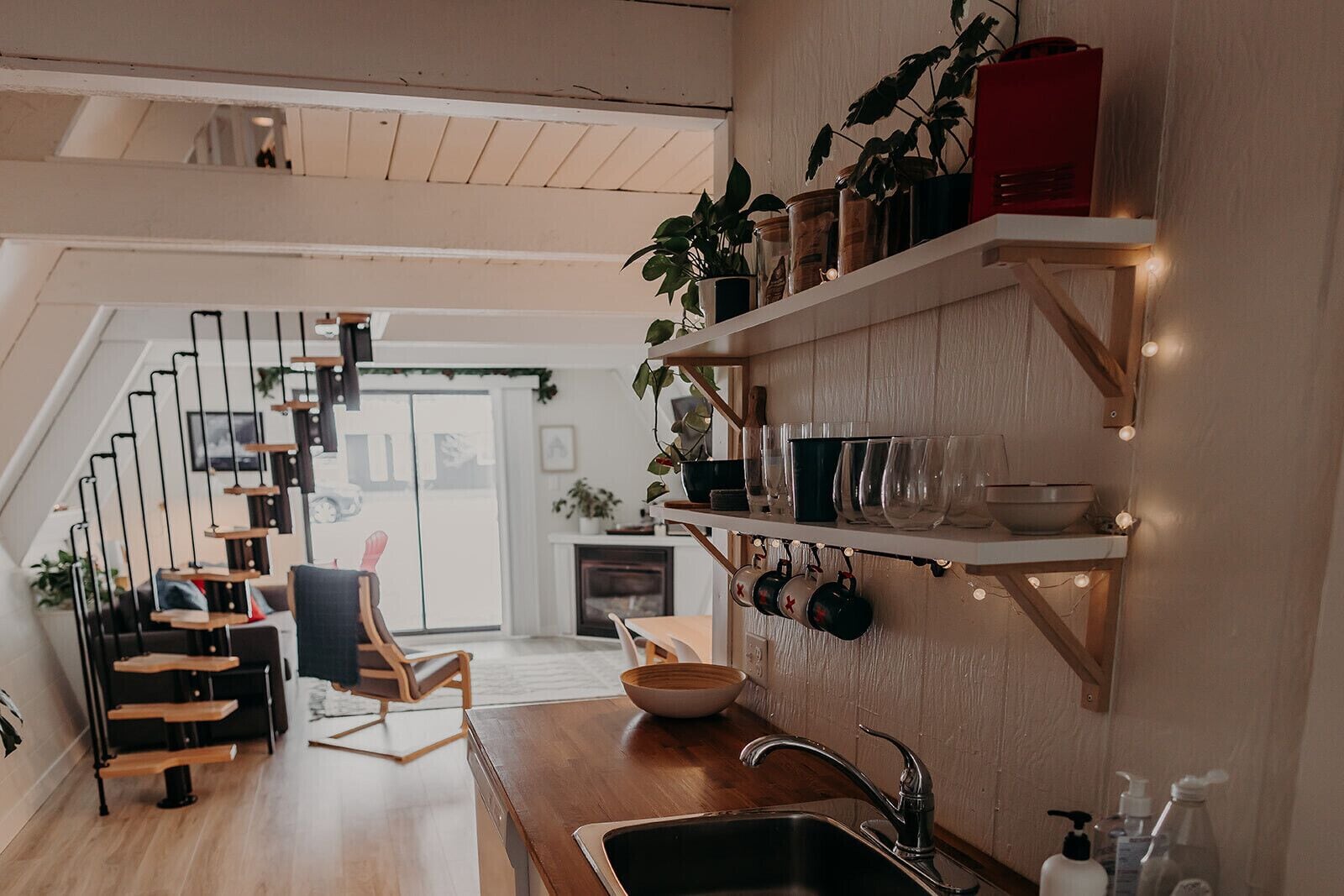 A modern kitchen with a wooden staircase, a dining area, and a kitchen island.