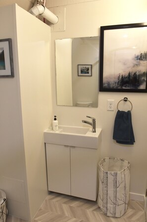 Une salle de bain avec un lavabo blanc, un miroir et un porte-serviettes.