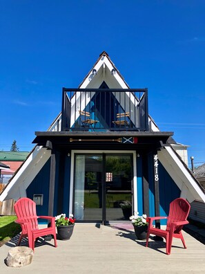 Un bâtiment doté d’un toit triangulaire et d’un balcon avec deux chaises rouges.