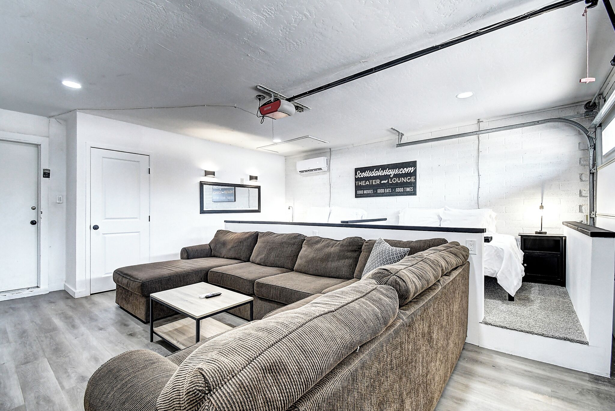 En moderne stue med en modulsofa, et lille bord og en seng i et hjørne.
