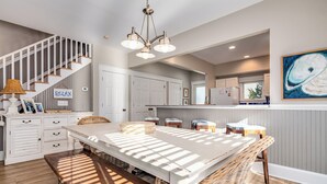 A spacious kitchen with a large island, white cabinetry, and a hanging light fixture.