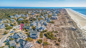 An aerial view of a coastal residential area with houses, a beach, and a boardwalk.