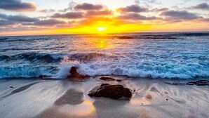 A beach with waves and a sunset.