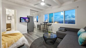 A modern living room with a bed, a sofa, a dining area, and a TV. - Modern Studio - Stunning Views! Centrally Located! (San Diego)