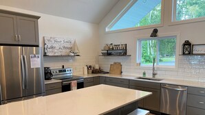 Una cocina moderna con una isla grande, electrodomésticos de acero inoxidable y un letrero de estilo rústico.