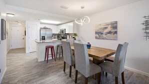 Una cocina moderna con armarios blancos, una mesa de comedor de madera y sillas tapizadas en gris.