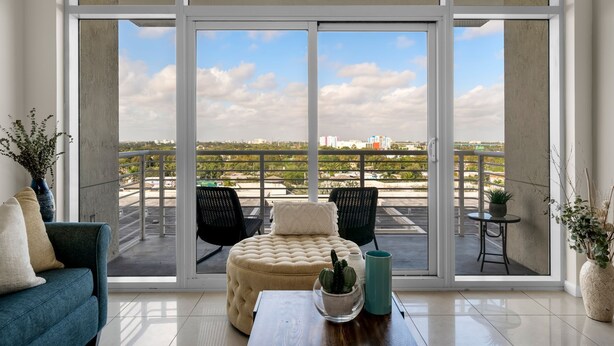 A spacious balcony with a view of the cityscape, furnished with a sofa, chairs, and a small table with decorative items.