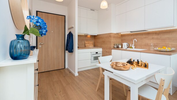 A modern kitchen with white cabinets, a wooden countertop, and a chessboard on the table. - Baltico Studio Apartment (Gdansk)