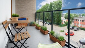 A balcony with a wooden table, chairs, and potted plants. - Baltico Studio Apartment (Gdansk)